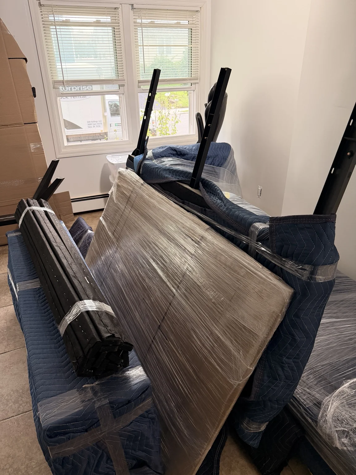 Furniture carefully wrapped in blue moving blankets and protective stretch film