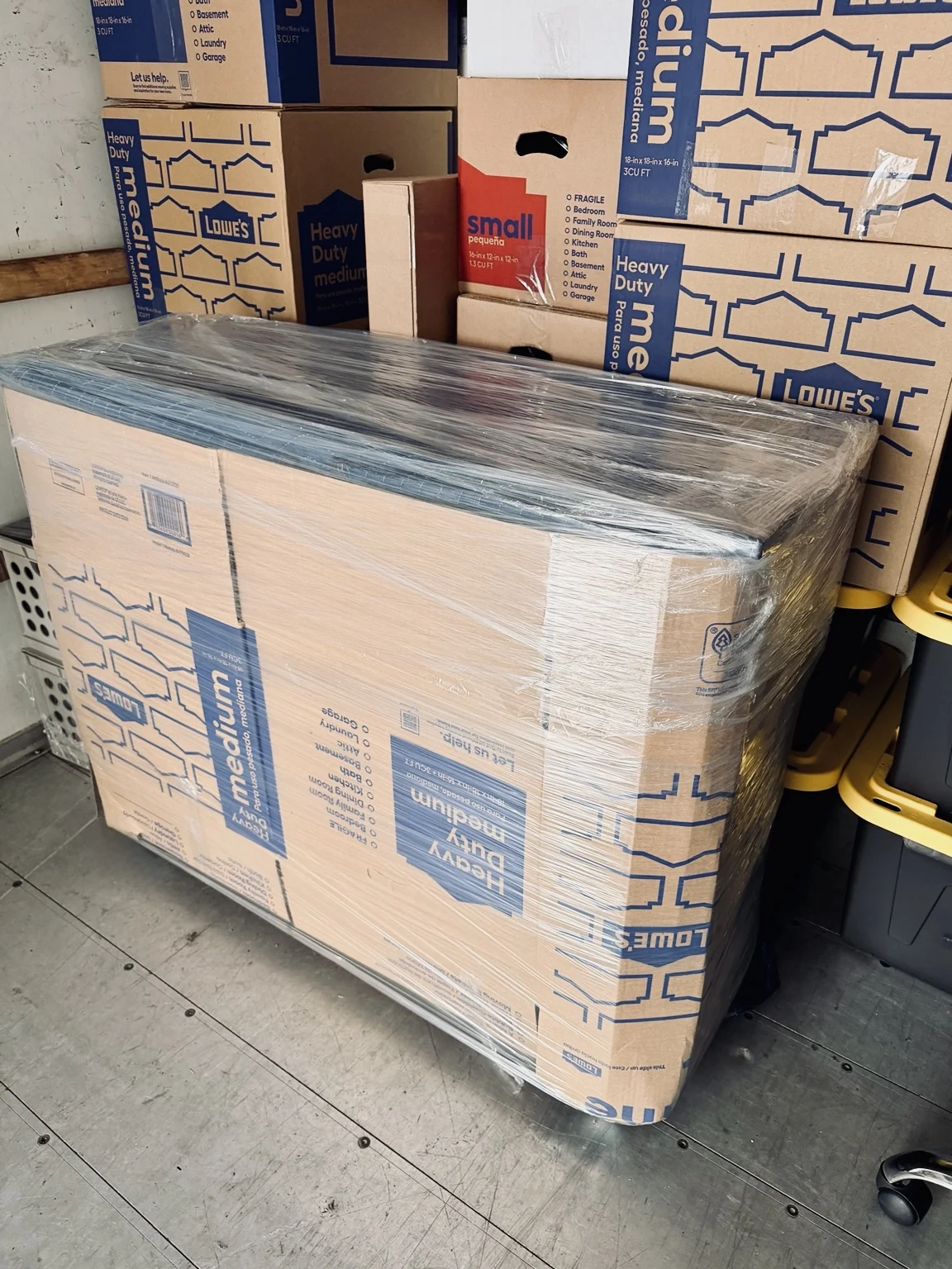 Packed moving boxes and a large item secured with protective stretch wrap inside a moving truck