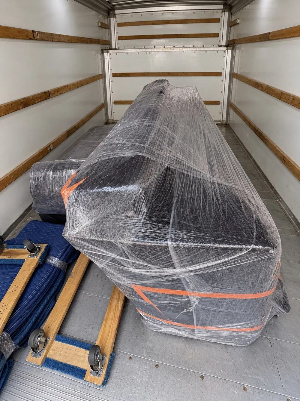 Furniture covered with blankets and shrink wrap inside a moving truck