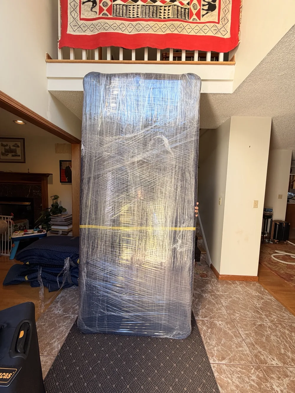 A tall furniture piece wrapped in blankets and protective film inside a home