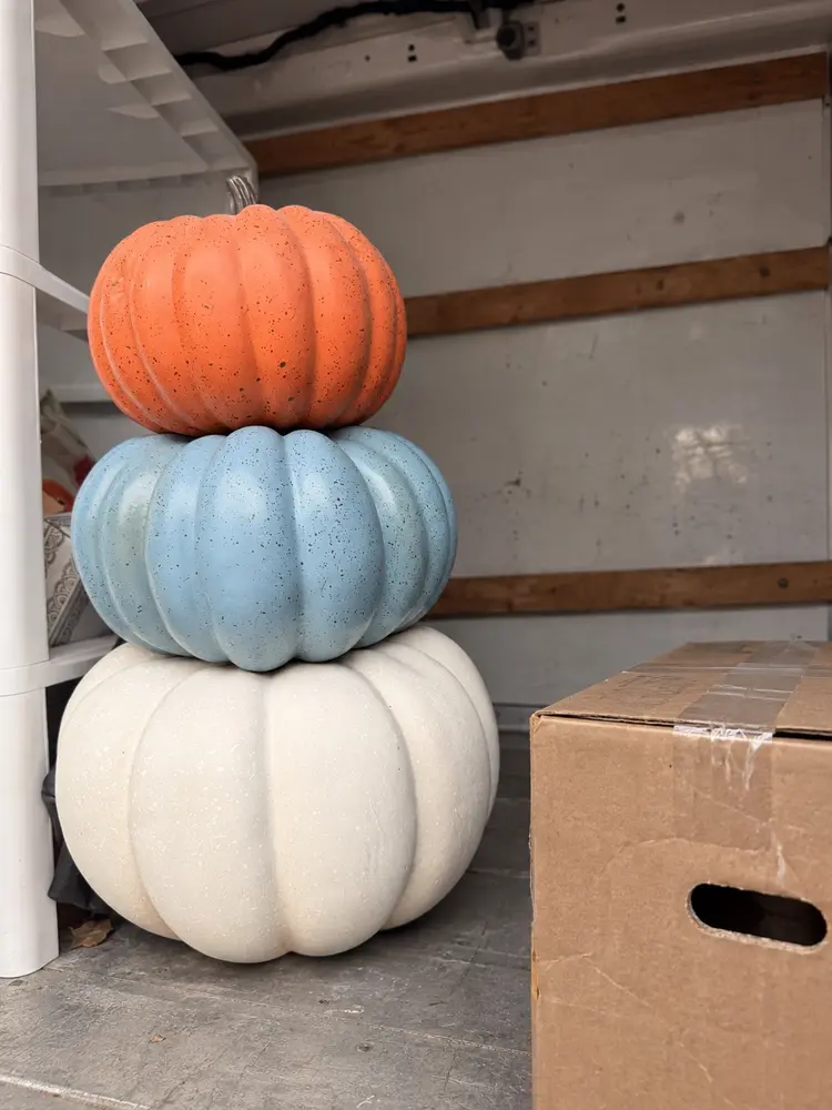 Orange, blue and white decorative pumpkins beside a moving box inside a truck